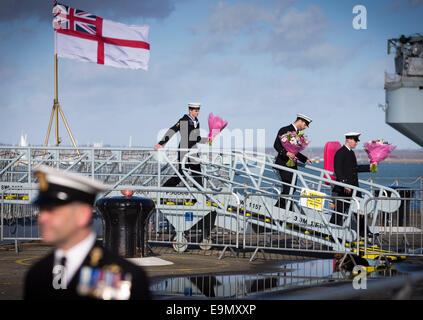 Ufficiali con mazzi di fiori di attendere pazientemente a bordo come il tipo 23 fregata HMS Richmond ritorna a Portsmouth Royal Navy Bas Foto Stock