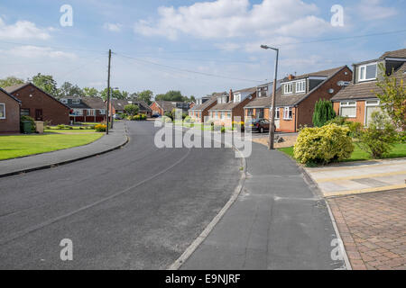 Una strada urbana con bungalows su entrambi i lati della strada con lo spazzamento strade a sinistra. Foto Stock