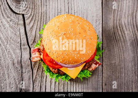 Hamburger con grigliate di carne e di formaggio e pancetta affumicata su una superficie in legno Foto Stock