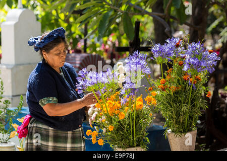 Un anziano zapoteco donna indigena organizza fiori e pulisce la tomba di parenti durante il Giorno dei Morti Festival noto in spagnolo come d'un de Muertos Ottobre 30, 2014 nel piccolo villaggio di Teotitian del Valle, Oaxaca, Messico. Foto Stock