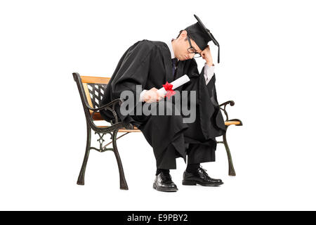 Triste studente laureato seduto su una panca in legno isolato su sfondo bianco Foto Stock