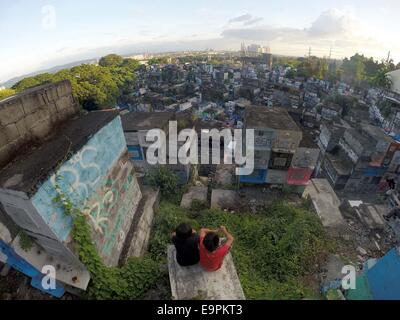 Marikina City, Filippine. 31 ott 2014. I bambini a sedersi su una tomba il giorno prima del giorno di tutti i santi in un cimitero di Marikina City, Filippine, il 31 ott. 2014. Milioni di persone di onorare i morti visitando i loro parenti defunti in vari cimiteri durante il giorno di Tutti i Santi e la Commemorazione di tutti i defunti nelle Filippine. © Rouelle Umali/Xinhua/Alamy Live News Foto Stock