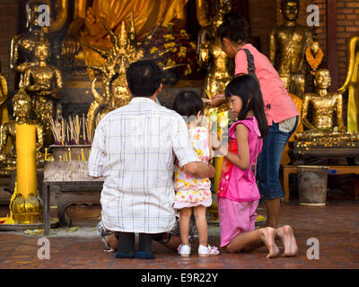 Buddista tailandese famiglia pregare e di compiere sacrifici davanti al santuario buddista di Tempio antico in Ayutthaya, Thailandia. Foto Stock