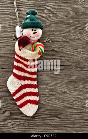 Calza di Natale con pupazzo di neve e candy cane contro uno sfondo di legno Foto Stock