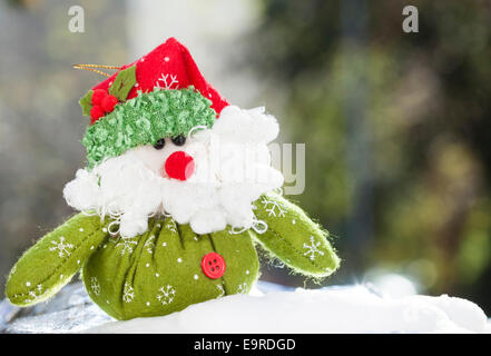 Decorazione di natale con closeup sul verde Santa Claus figurina nella neve Foto Stock