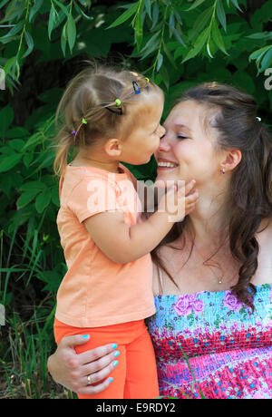 Bambina teneramente baci e abbracci madre. Foto Stock