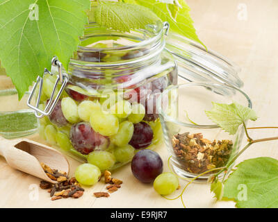 Vaso di vetro con le conserve di uve, mosto di foglie e spice sul tavolo di legno Foto Stock