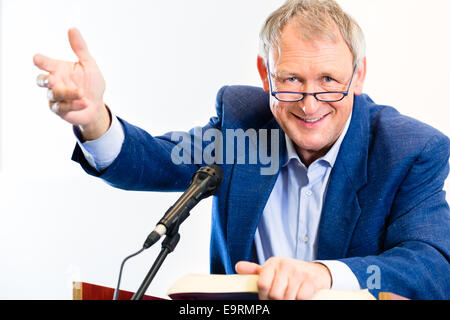 Professore universitario dando lezioni e permanente al desk Foto Stock