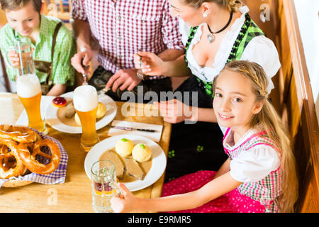 Ragazza bavarese indossando dirndl e mangiare con la famiglia nel ristorante tradizionale Foto Stock