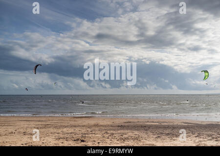 Kite surfers in una giornata ventosa a Exmouth nel Devon, Regno Unito. Buone condizioni per il kite surfing contro un cielo drammatico e orizzonte. Foto Stock