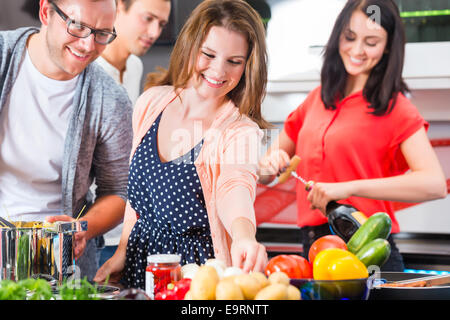Amici cucinare gli spaghetti e carne in cucina domestica Foto Stock