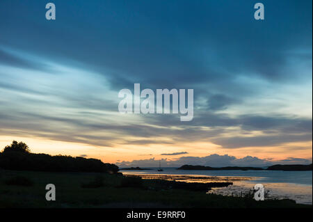 Skyscene del tramonto su solitario barche da pesca sul Loch Dunvegan, l'Isola di Skye in Scozia Foto Stock