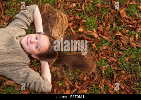 Сute ragazza distesa sulla caduta foglie in autunno park. Foto Stock