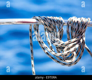 Funi o mainsheets sul ponte della barca a vela appeso su uno sfondo di colore blu acqua di mare. Foto Stock