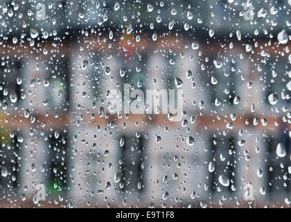 Edificio visibile attraverso il vetro ricoperto da gocce di pioggia Foto Stock