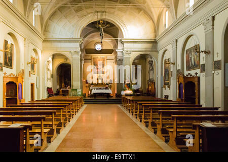 La Chiesa dell'Assunzione della Vergine Maria nel piccolo villaggio di Dozza vicino a Bologna in Emilia Romagna: interni: Croce, altare, scrivanie, panchine, dipinti, candele Foto Stock