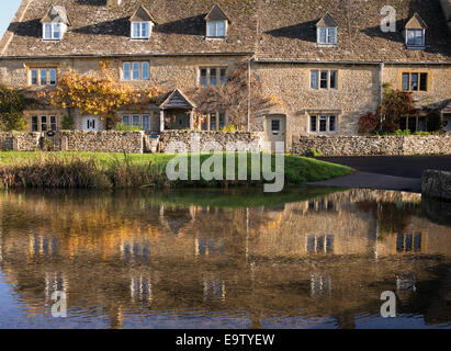 Cottage e riflessioni sul fiume in autunno sunshine. Macellazione inferiore. Cotswolds, Gloucestershire, Inghilterra Foto Stock