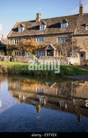 Cottage e riflessioni sul fiume in autunno sunshine. Macellazione inferiore. Cotswolds, Gloucestershire, Inghilterra Foto Stock