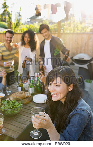 Donna sorridente di bere vino a backyard barbecue