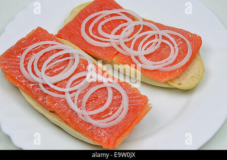 Sandwich di salmone con anelli di cipolla sulla piastra bianca, close up Foto Stock