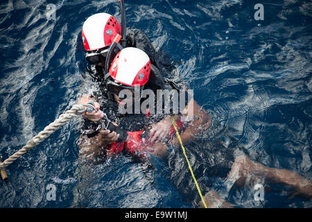 Stati Uniti Navy Ensign Julian G. Abellar, foreground, assegnato all'guidato-missile fregata USS Vandegrift (FFG 48), le pratiche di ricerca e soccorso con tecniche della nave 2 Veteran Class Danielle Turner durante un drill ott. 21, 2014, nell'Oceano Pacifico. Il Foto Stock