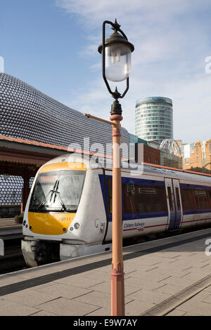 Un Chiltern Railways treno attende presso la piattaforma in Birmingham Moor Street Station, dietro,Selfridges, Rotunda e il Bullring Foto Stock