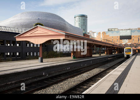 Un Chiltern Railways treno attende presso la piattaforma in Birmingham Moor Street Station, dietro,Selfridges, Rotunda e il Bullring Foto Stock