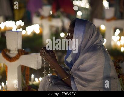 Dacca in Bangladesh. 2° Nov, 2014. Devoti cristiani osservare il giorno della commemorazione di tutti i defunti, conosciuta anche come la festa di tutte le anime, alla Chiesa Tejgaon. In questo giorno, i cristiani venuti al cimitero e a pregare per i defunti dei loro cari. La Chiesa cattolica romana holiday deriva dall'antica festa pagana dei morti, che ha celebrato il Pagan credenza che le anime dei morti potrebbe tornare per un pasto con la famiglia. Candele in la finestra che guida le anime di tornare a casa e un posto extra è stata impostata al tavolo. © Zakir Hossain Chowdhury/ZUMA filo/Alamy Live News Foto Stock