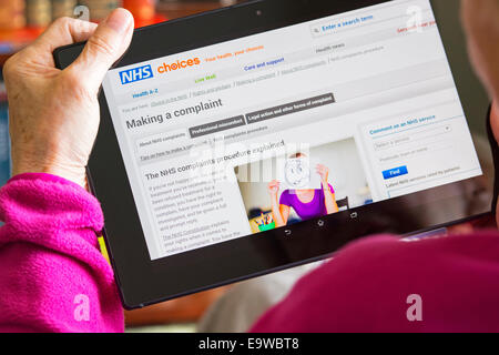 Sito web di NHS Schermo, denunce su Tablet, Donna lettura Foto Stock