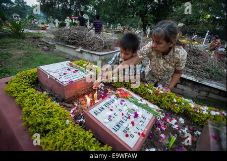 Calcutta, India. 2° Nov, 2014. I cristiani indiani accendono le candele sulle tombe dei parenti in un cimitero cattolico durante la commemorazione di tutti i defunti a Calcutta, India, nov. 2, 2014. Commemorazione di tutti i defunti è un cattolico romano giorno osservata in ricordo per amici e cari scomparsi. © Tumpa Mondal/Xinhua/Alamy Live News Foto Stock