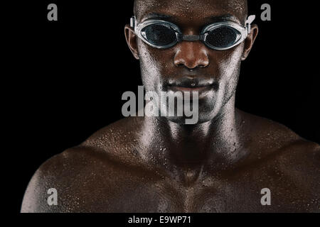 Giovane africano con gli occhiali per nuoto isolate su sfondo nero. Nuotatore con corpo bagnato. Foto Stock