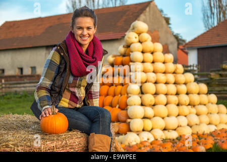 Ritratto di giovane donna seduta sul pagliaio con zucca nella parte anteriore delle righe di zucca Foto Stock