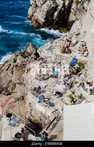 I turisti rilassarsi, prendere il sole e nuotare lungo la base delle mura della città di Dubrovnik Città Vecchia, Croazia. Foto Stock