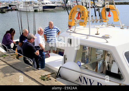 Un gruppo di pescatori listning alle istruzioni prima di intraprendere una giornata di pesca dal porto di Poole, Dorset, Inghilterra, Regno Unito. Foto Stock