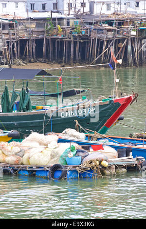 Cinese in legno barca da pesca con il Tai O villaggio di case su palafitte in background, l'Isola di Lantau, Hong Kong. Foto Stock