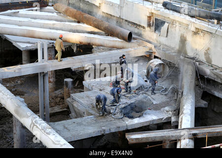 I lavoratori che operano in corrispondenza di un sito in costruzione presso il cantiere per la costruzione di un edificio di grandi dimensioni Foto Stock