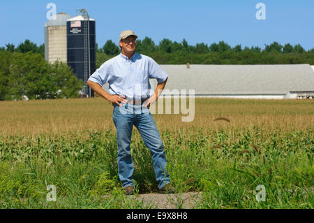 Un agricoltore sta ispezionando i suoi campi con silos per il grano e da un fienile in background / vicino a Hoffman, Minnesota, Stati Uniti d'America. Foto Stock