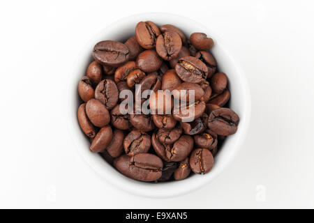 Di piccole dimensioni e di colore bianco tazzina piena di freschi chicchi di caffè tostati su sfondo bianco, vista dall'alto Foto Stock