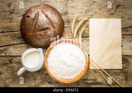 Bakery ricetta dello sfondo. Filone di pane di segale con ingredienti e carta bianca ricetta foglio su uno sfondo di legno Foto Stock