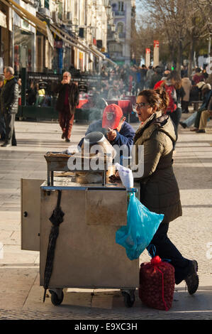 Ritratto verticale di gente che vende castagne arrostite a Lisbona. Foto Stock