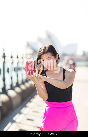Una giovane donna prendendo un 'selfie' all'aperto tirando una divertente volto Foto Stock