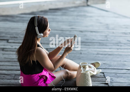 Una giovane donna asiatica di consumare il contenuto sullo smartphone all'aperto Foto Stock