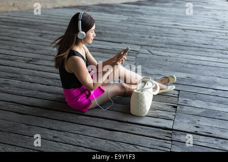 Una giovane donna asiatica utilizza il suo dispositivo mobile Foto Stock