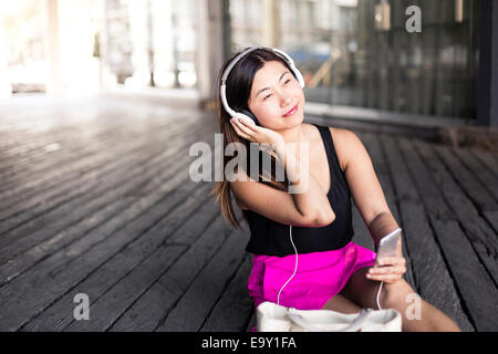 Una giovane donna asiatica utilizza il suo dispositivo mobile Foto Stock