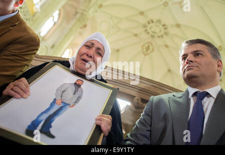 Berlin-Moabit, Germania. 04 Nov, 2014. Madre di omicidio vittima Semiya O., accompagnato dai suoi avvocati Mehmet Daimaguler (R), contiene un'immagine del suo figlio assassinato al di fuori delle aule di tribunale presso il tribunale penale di Berlin-Moabit, Germania, 04 novembre 2014. La prova inizia martedì contro undici bikers che sono incaricati di uccidere un 26-anno-vecchio uomo in un agenti di scommesse a Berlino nel gennaio del. Foto: Matthias esitano di fronte/dpa/Alamy Live News Foto Stock