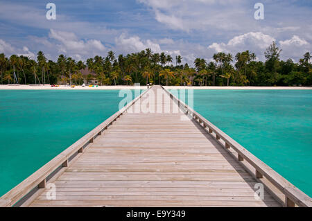 Pontile in legno per un po' di isola tropicale del turchese oceano indiano, Maldive. Foto Stock