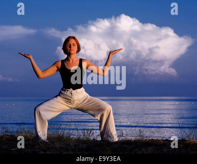 Giovane donna fare yoga al di fuori Foto Stock