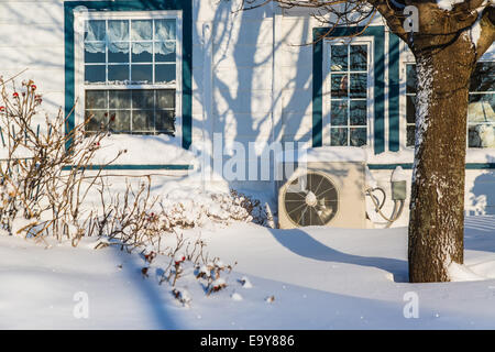 Unità a pompa di calore sul lato di una casa in inverno. Foto Stock