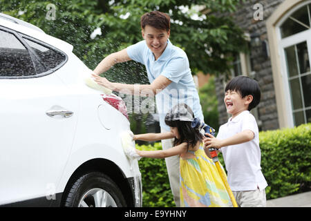 Un ragazzo e una ragazza, aiutando il padre la pulizia auto Foto Stock