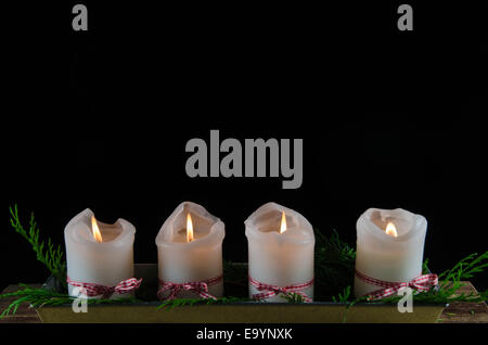 Quattro burning avvento candele ad uno sfondo nero Foto Stock